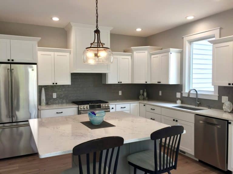 Modern kitchen with white cabinets, stainless steel appliances, an island, and pendant light.