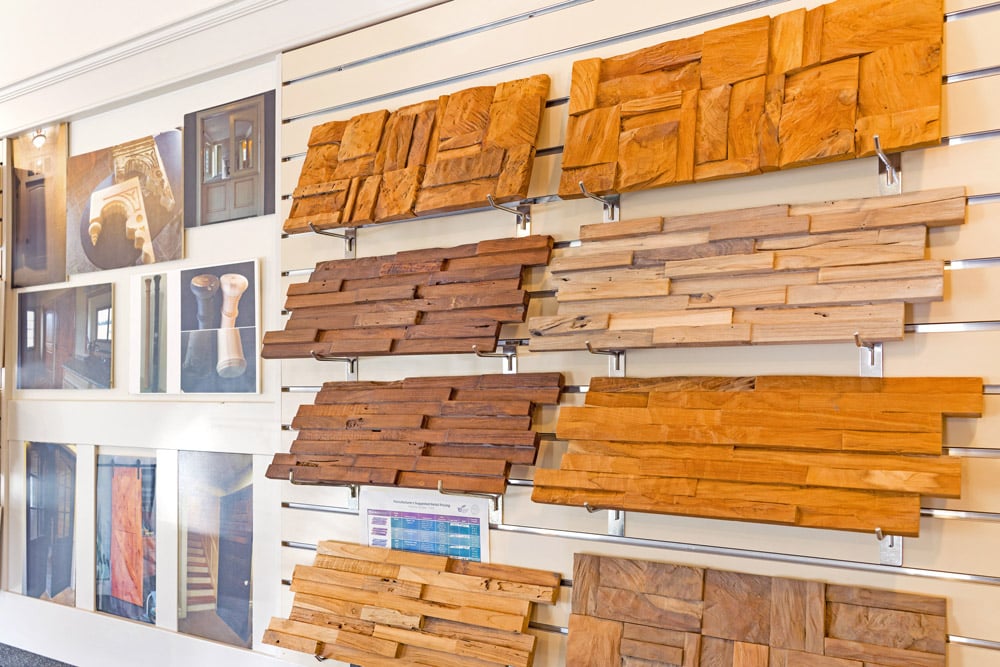Wood samples and photos are displayed on a showroom wall to showcase textures and finishes for interior design.