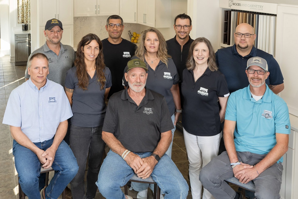 A group of eleven adults pose together in the showroom.